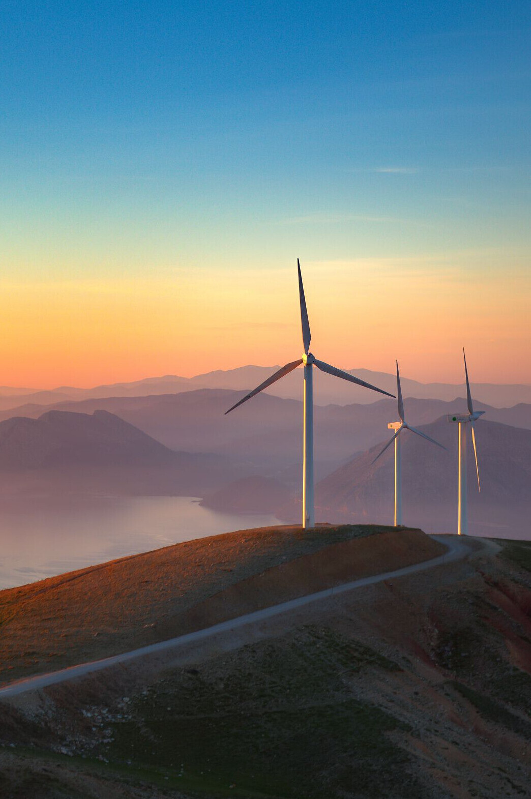 Wind turbine on green hills and sunset colours